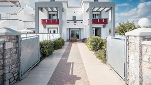 Un bâtiment moderne doté d’une entrée centrale, d’une galerie couverte et d’un mur en pierre sur l’un de ses côtés.