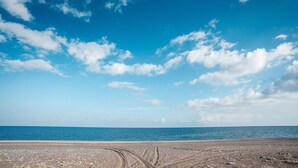 Une plage avec un ciel dégagé et une mer calme.