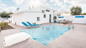 Un bâtiment moderne doté d’une piscine, de chaises longues et d’une table avec des chaises.