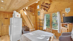 Eine Holzhütte mit Kühlschrank, Tisch mit herzmusteriger Tischdecke, montiertem Tierkopf und Fernseher.