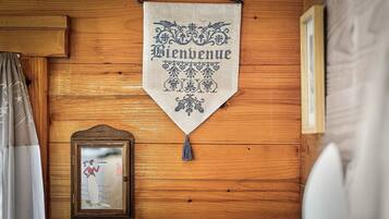 A wooden wall with a hanging welcome banner, a framed picture, and a curtain.
