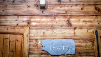 Un mur en bois sur lequel est fixée une plaque d’ardoise portant l’inscription « LE MAZET ».