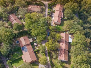 An aerial view of a residential area with multiple houses, each with a red-tiled roof, surrounded by greenery.