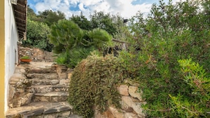 A stone staircase leading to a building with a yellow exterior, surrounded by lush greenery and a stone wall. - Vacation Home 'Il Lentischio - Rosmarino' in Cala Lunga 200 Metres from the Sea (Sant'antioco)