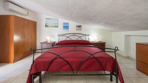 A bedroom with a bed, wooden wardrobe, bedside tables, and a ceiling fan. - Vacation Home 'Il Lentischio - Rosmarino' in Cala Lunga 200 Metres from the Sea (Sant'antioco)
