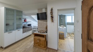 Cozinha moderna com micro-ondas, armário de madeira e televisão fixada na parede.