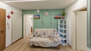 Um quarto aconchegante com um sofá, uma prateleira branca, um relógio e decorações em formato de coração.