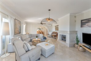 A spacious living room with a sectional sofa, a fireplace, a television, and a ceiling fan. - Villa 'Villa in Mijas Golf' with Sea View, Wi-Fi and Air Conditioning (Mijas)