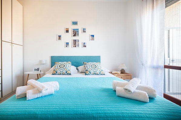 Une chambre d’hôtel avec un lit, des oreillers, une table de chevet, un mur décoré de tableaux et une fenêtre.