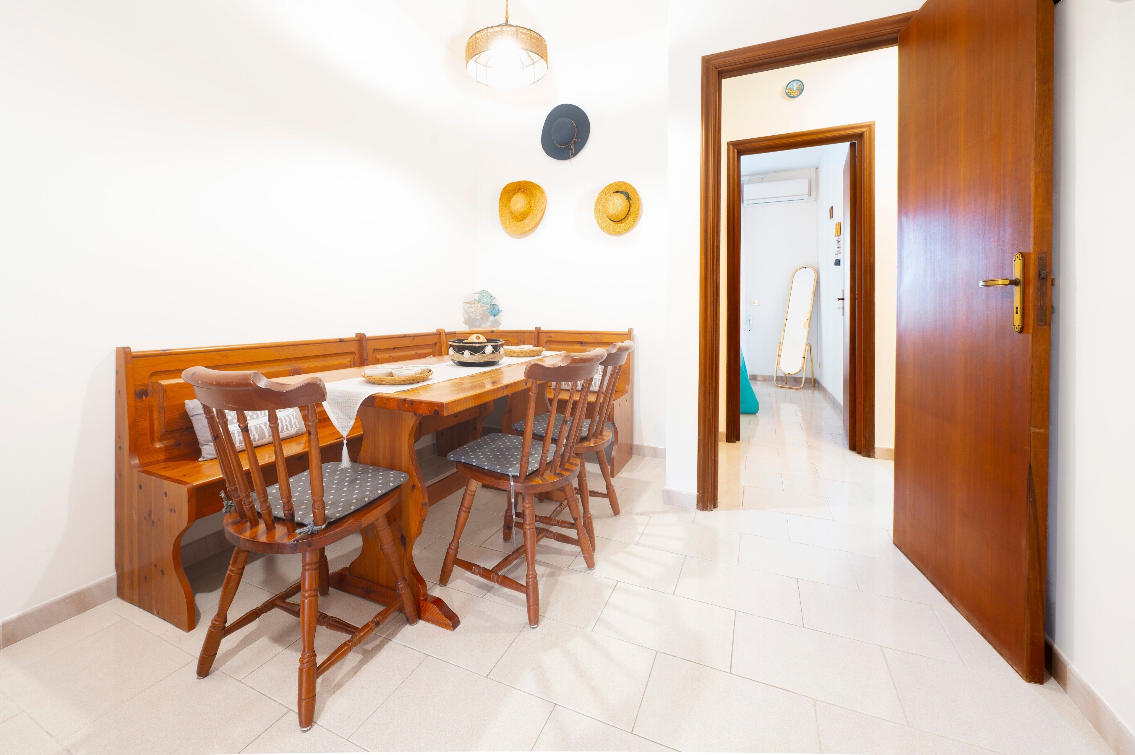 A dining area with a wooden table and chairs, a bench, and a door leading to another room.