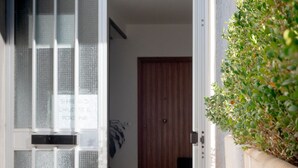 Un passage donnant sur une pièce dont la porte est en bois, avec une plante en pot placée à côté.