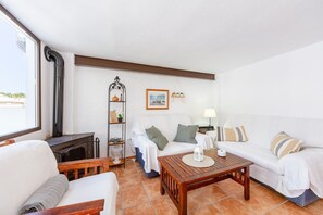 A living room with a sofa, armchair, wooden coffee table, and a fireplace. - La Casa de la Buhardilla – Rural House with Sierra Nevada Views in Fondón (Fondón)