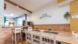 Un coin repas avec une table en marbre et des chaises blanches, une cuisine en arrière-plan et une enseigne indiquant « CASA BUHARDILLA ».
