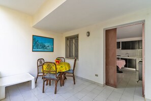 Un comedor con una mesa, sillas, un banco, un cuadro y vista a una cocina.