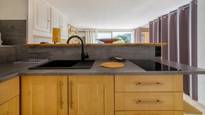 A modern kitchen with a black sink, wooden cabinets, and a built-in stove.