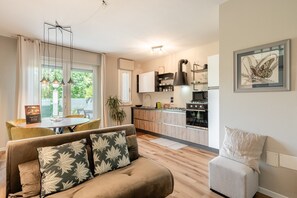 En moderne stue med en sofa, et spisebord og et køkken i baggrunden.