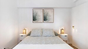 A bedroom with a bed, two bedside tables with lamps, and two wall-mounted artworks. - Apartment 'Jardim Da Parada' with Wi-Fi and Air Conditioning (Cascais)