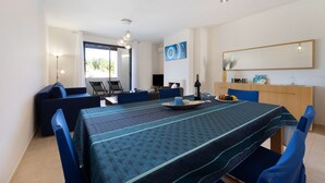 A dining area with a table set for two, a sofa, and a chair. - Apartment 'Duo Village' with Shared Pool, Wi-Fi and Air Conditioning (Alvor)