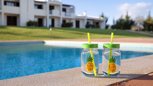 Two clear glass bottles with green lids and yellow straws, placed on a poolside ledge. - Apartment 'Duo Village' with Shared Pool, Wi-Fi and Air Conditioning (Alvor)