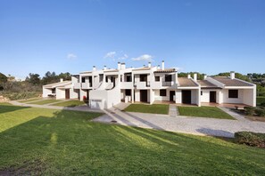 A modern multi-story residential building with a spacious courtyard, multiple balconies, and a clear sky.