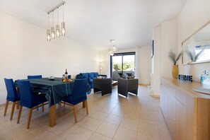 A modern dining area with a table, chairs, and a kitchen counter. - Apartment 'Duo Village' with Shared Pool, Wi-Fi and Air Conditioning (Alvor)