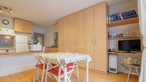 Eine kompakte Küche mit Esstisch, Stühlen, Kühlschrank, Mikrowelle und Fernseher.