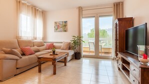 A living room with a sofa, a coffee table, a TV, and a balcony with a view.