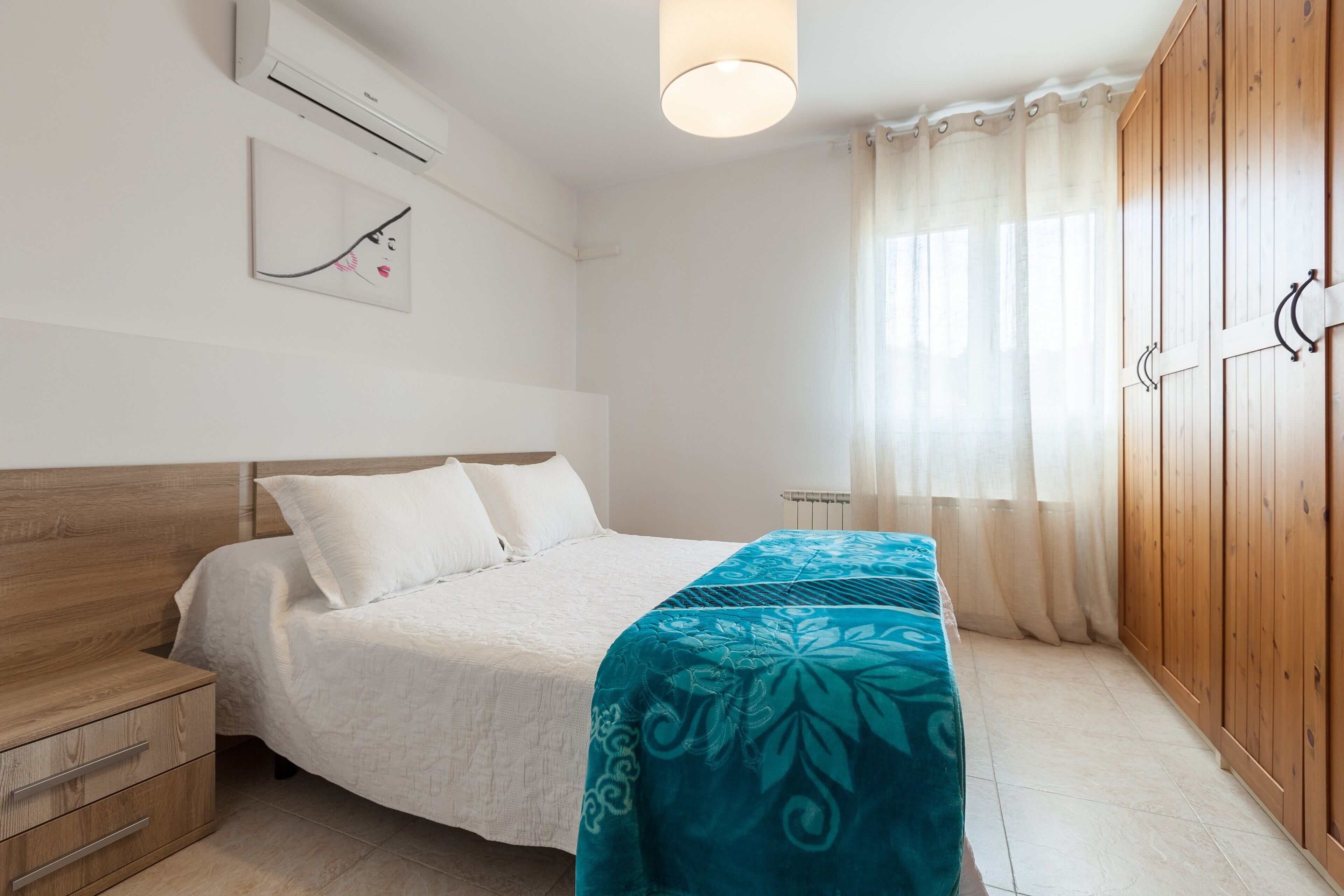 Une chambre à coucher comprenant un lit, une table de chevet, une armoire et un climatiseur fixé au mur.