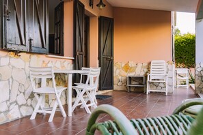 A patio with stone walls, a table, and white chairs. - Holiday Home 'Villa Carola' with Mountain View, Wi-Fi and Air Conditioning (Quartu Sant'Elena)