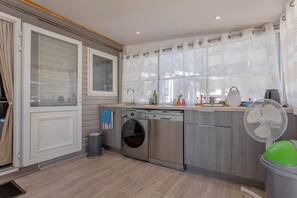 Una cucina moderna con lavatrice integrata, un lavandino e una ventola.