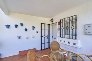 A patio area with a table and chairs, a potted plant, and a door with a security gate.