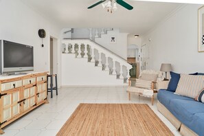 A living room with a television, sofa, and a staircase leading to an upper floor.