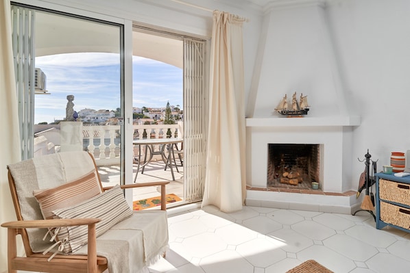A room with a sofa, a fireplace, and a view of the city.