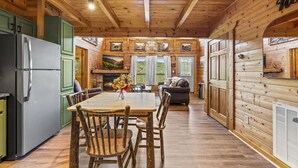 A wooden cabin interior with a dining area, kitchen, and living space.