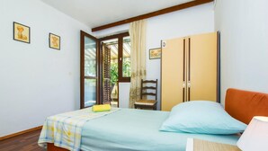A bedroom with a bed, a chair, a wardrobe, and a window with curtains. - 1 bedroom lovely apartment in Split (Split)