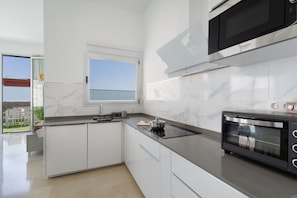 Une cuisine moderne avec des meubles blancs, un four à micro-ondes encastré et une fenêtre offrant une vue agréable.