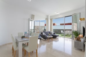 Un salon moderne comprenant un coin repas, un canapé, un téléviseur et un balcon avec vue.