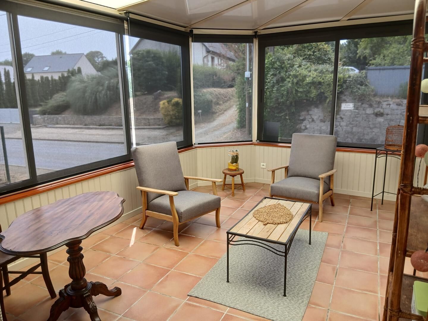 A conservatory with two chairs, a table, and a view of the outside.