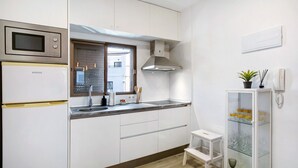 A modern kitchen with a microwave, oven, and sink. There is a window with blinds, a white cabinet, and a small stool. - Vacation Apartment 'Eras Views' with Sea View and Wi-Fi (Las eras)
