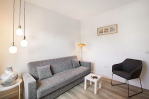 En moderne stue med en grå sofa, et hvidt sofabord, en sort lænestol og en gulvlampe.