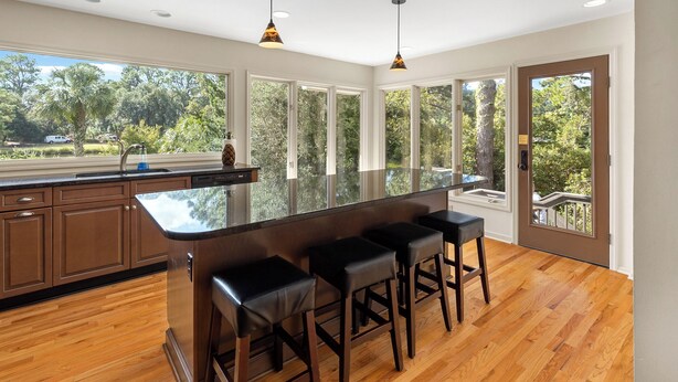 A modern kitchen with a large island, bar stools, and large windows offering a view of the outdoors. - Monthly Stays Available! Pool/WalkToBeach/1MileToSaltyDog/LagoonSetting/Relaxing (Hilton Head Island)