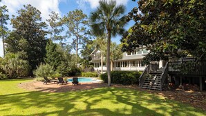 A two-story house with a swimming pool, surrounded by lush greenery and trees. - Monthly Stays Available! Pool/WalkToBeach/1MileToSaltyDog/LagoonSetting/Relaxing (Hilton Head Island)