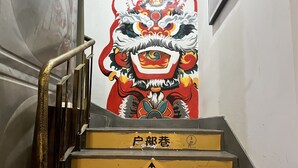 A staircase with a mural of a traditional lion dance figure. - enjoy youth hotel (Wuhan)