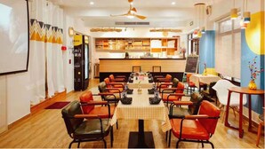 A restaurant with a long table set for dining, multiple chairs, a counter with a menu, and a ceiling fan. - enjoy youth hotel (Wuhan)