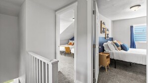 Une chambre à coucher avec un lit, une table de chevet, une commode et une fenêtre avec des rideaux bleus.