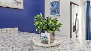 Une cuisine dotée d’un plan de travail en granit, d’une plante en pot et d’œuvres d’art encadrées accrochées au mur.