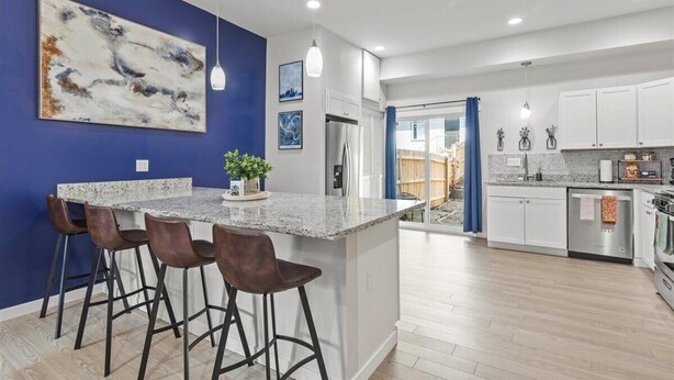 Une cuisine moderne avec un îlot central, des tabourets de bar et un mur d’accent bleu.