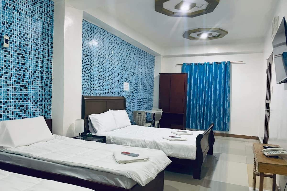 A hotel room with two beds, a desk, a chair, and a TV.