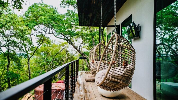 Una terraza de madera con una hamaca colgante y un contenedor rojo.