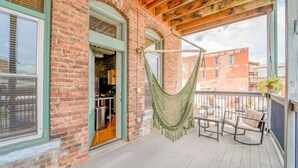 Een balkon met een hangmat, zitplaatsen buiten en uitzicht op de stad.